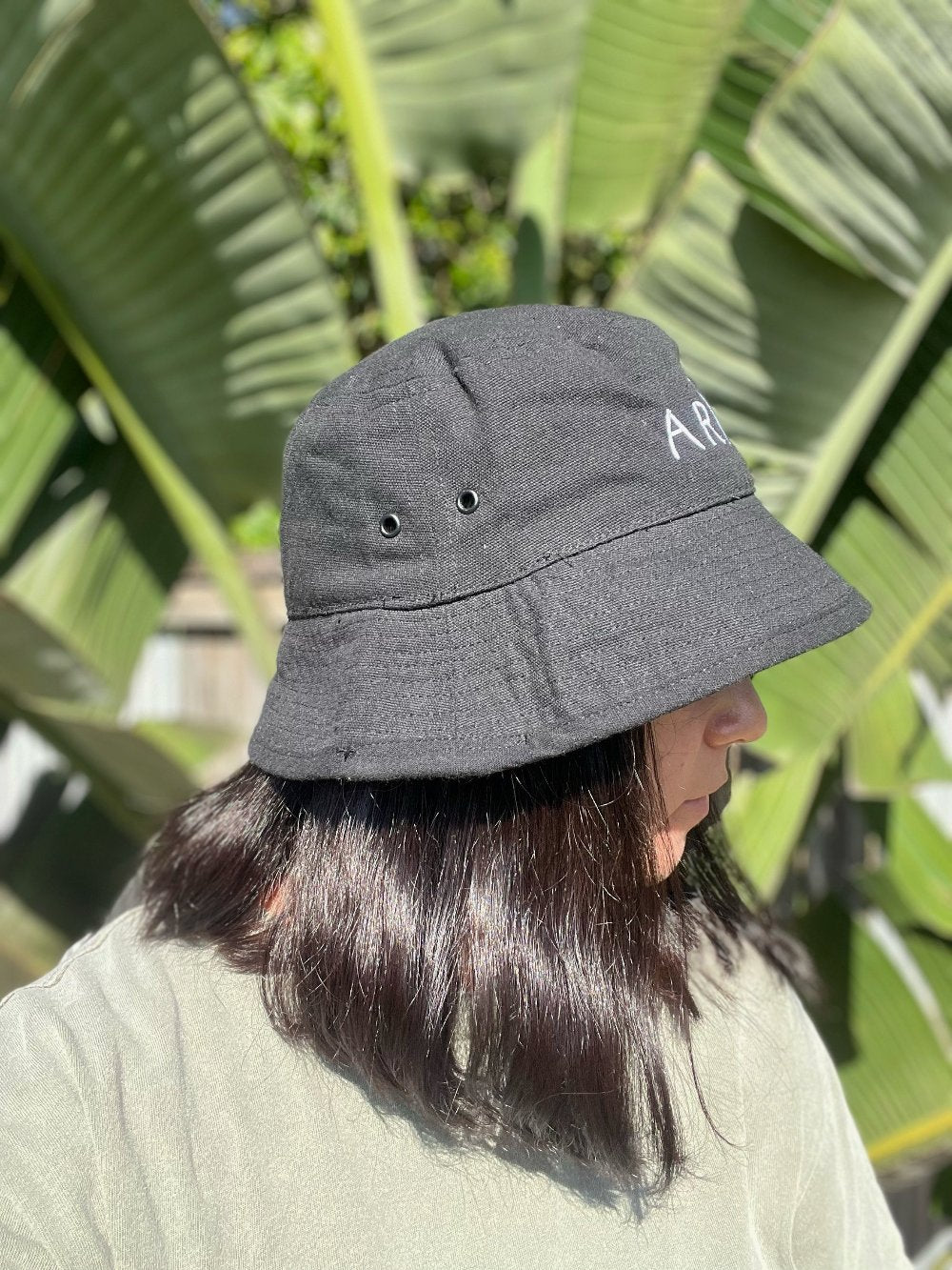 Black bucket hat made from recycled cotton and recycled polyester. Features a white embroidered logo. Available in sizes S/M and M/L. Ethically produced with certifications and shipped in eco-friendly packaging.