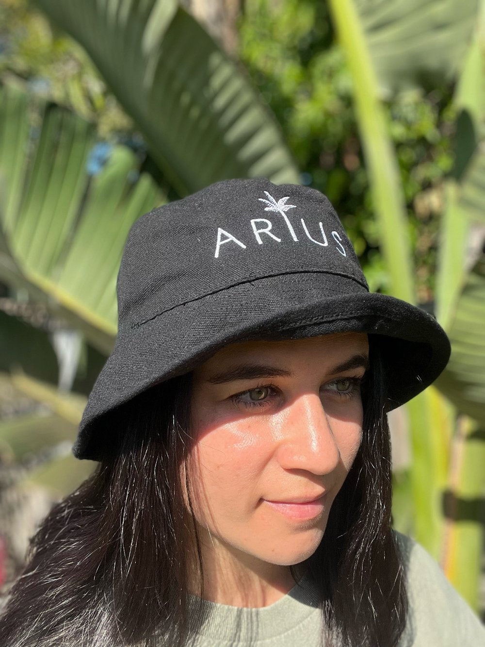 Black bucket hat made from recycled cotton and recycled polyester. Features a white embroidered logo. Available in sizes S/M and M/L. Ethically produced with certifications and shipped in eco-friendly packaging.